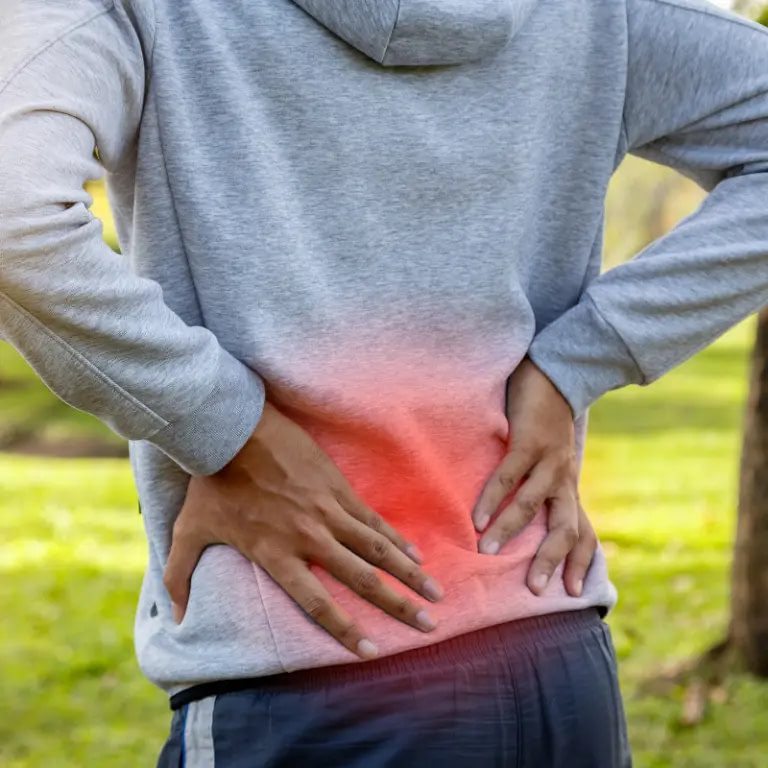 Person holding their lower back with pain highlighted across the lumbar area